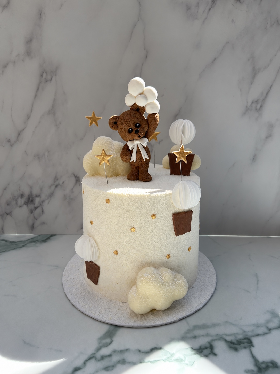 White velvet celebration cake with teddy bear, clouds and gold stars